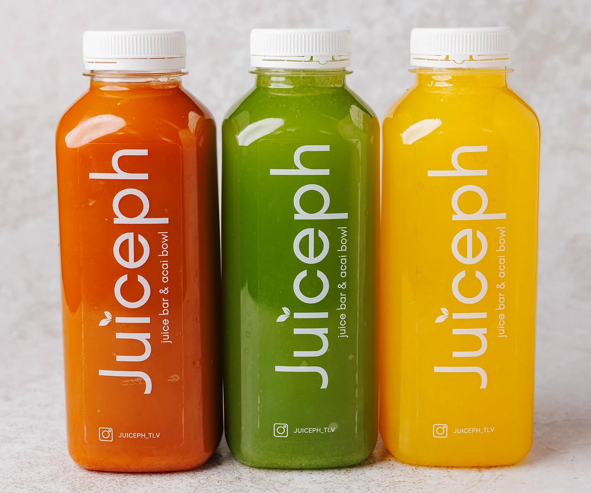 שלושה מיצים סחוטים טריים של JUICEPH בבקבוקים: כתום, ירוק וצהוב