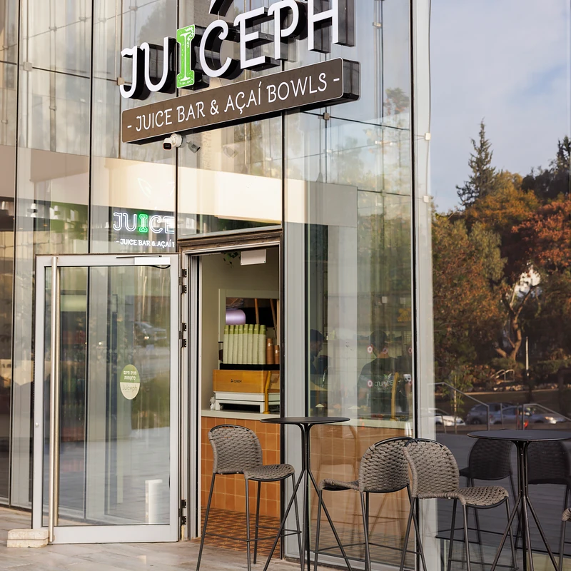 חזית סניף JUICEPH עם השלט והכיסאות בחוץ